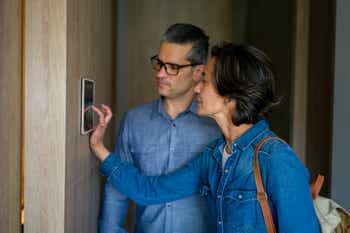 Couple leaving their house and locking the door using a smart home device