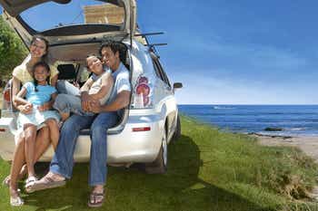 Family of four sitting in the back of a car on the beach