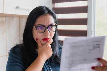 Worried woman checking bills at home