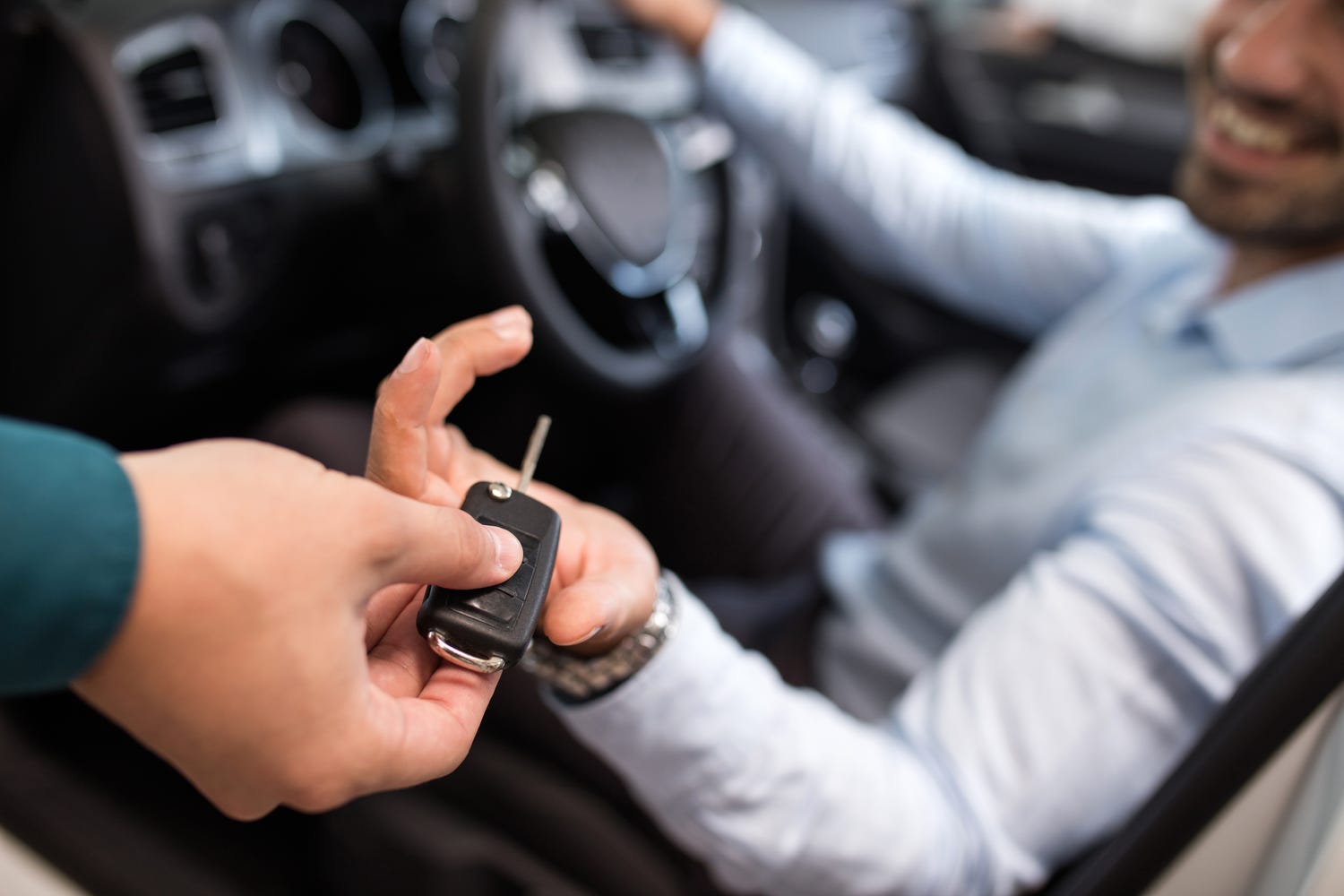 Car rental representative handing keys to a man in rental car