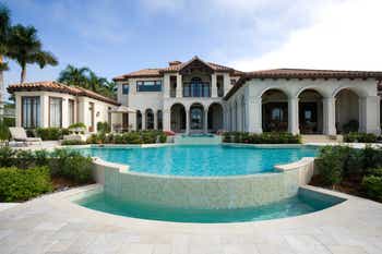 Beautiful estate home featuring a swimming pool surrounded by palm trees