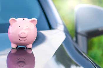Piggy bank sitting on the hood of a car