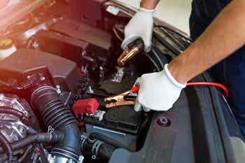 Mechanic using jumper cables to start a car