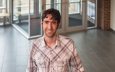 Benjamin Allen smiling at the camera in an academic building