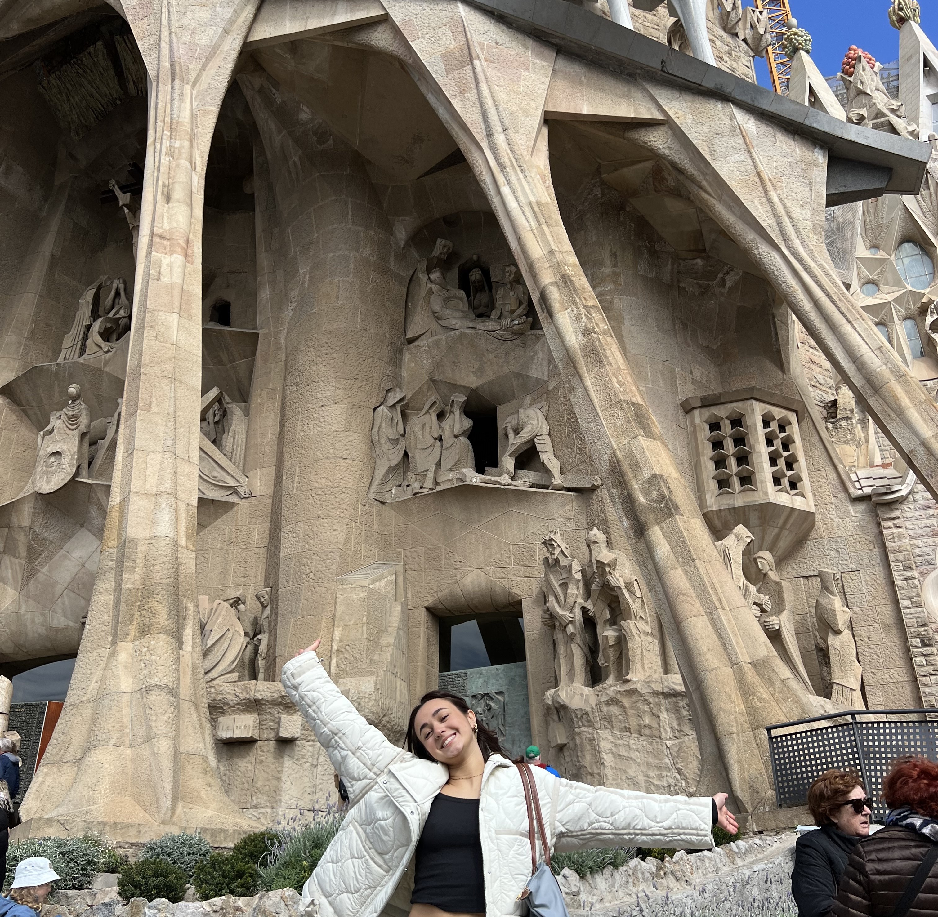 A student in a white jacket in front of a building and statues 