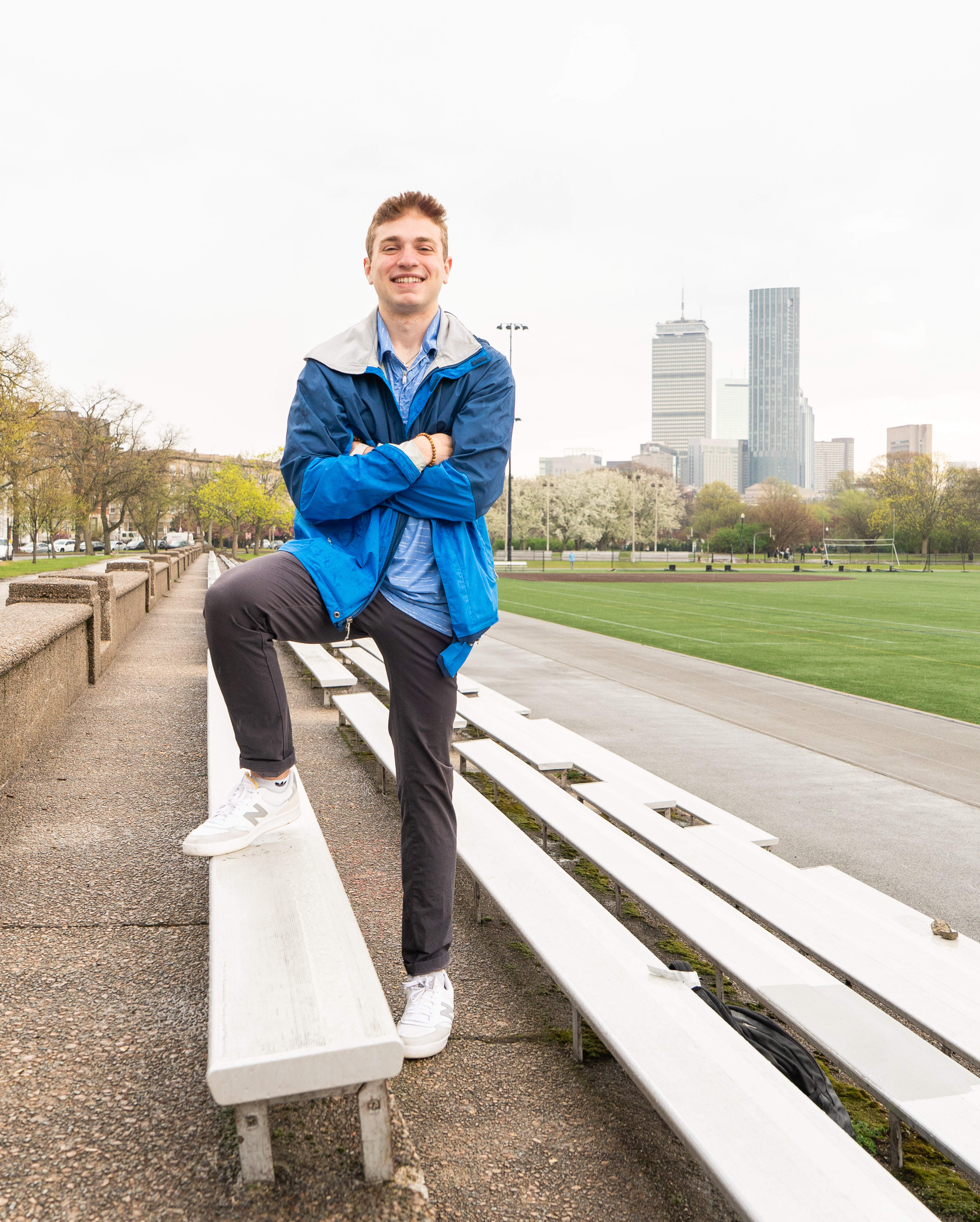 A man in a blue jacket in front of the Boston skyline 