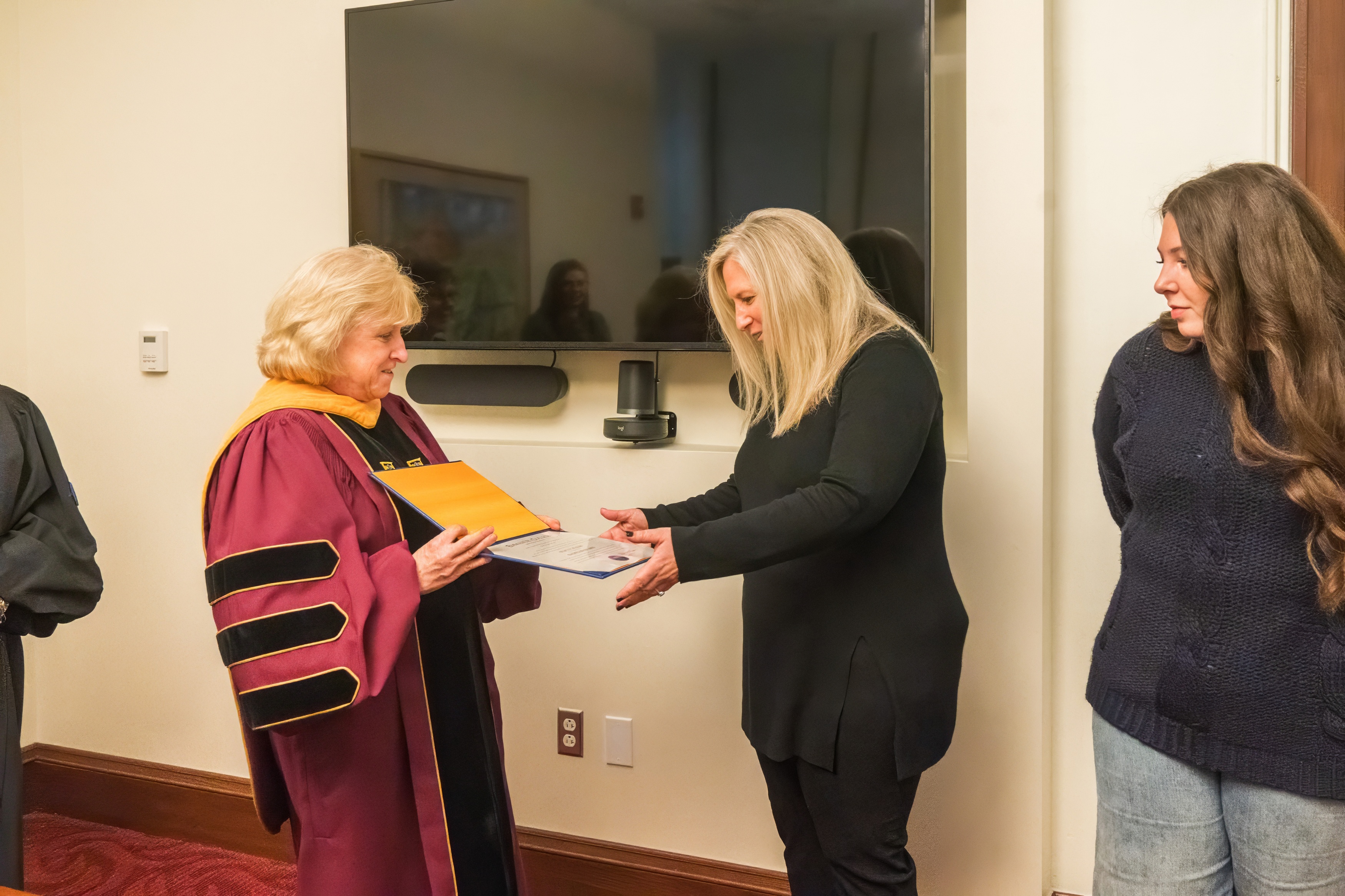 A professor presents a degree to a recent graduate 