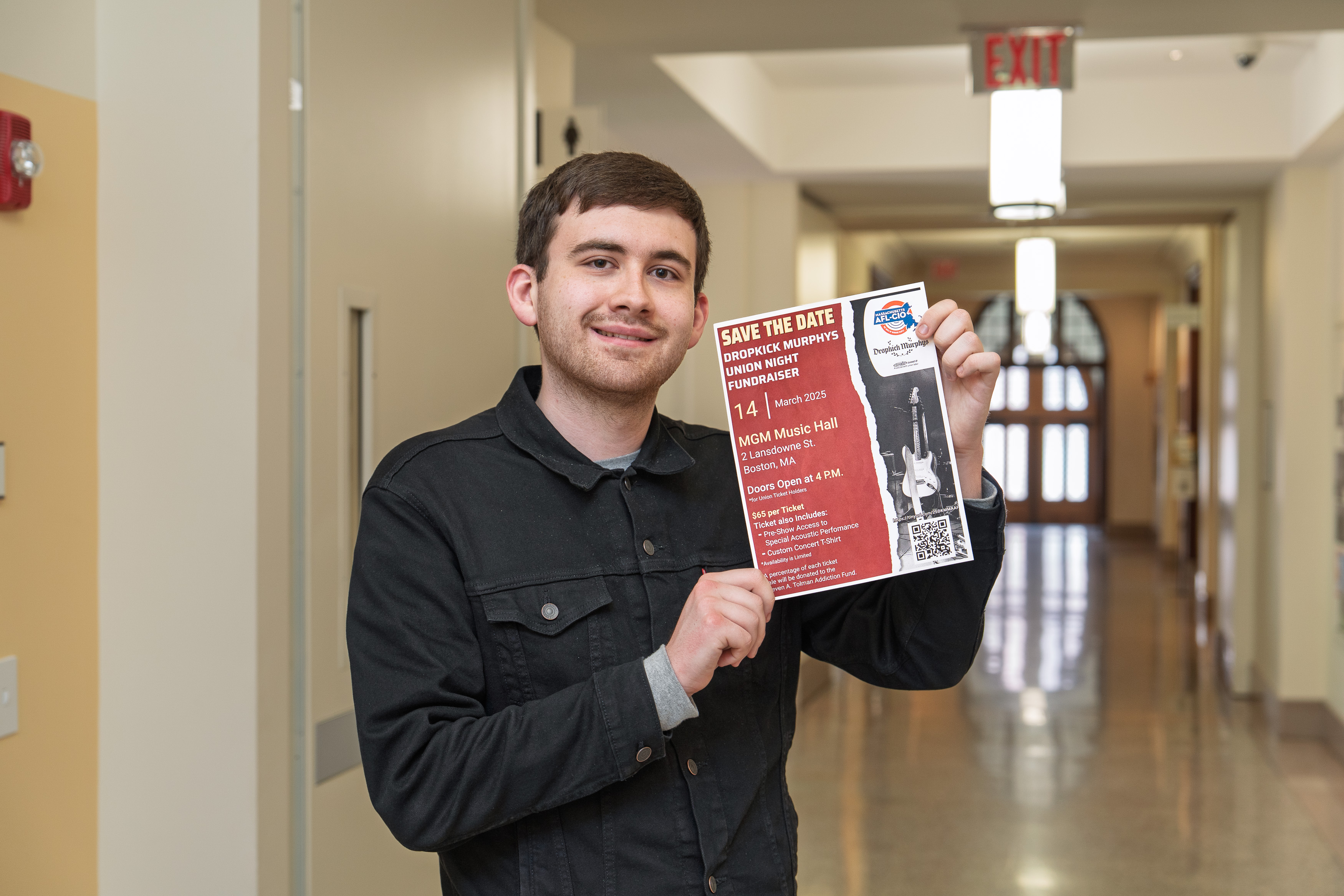 A young man with a black shirt holding a poster 