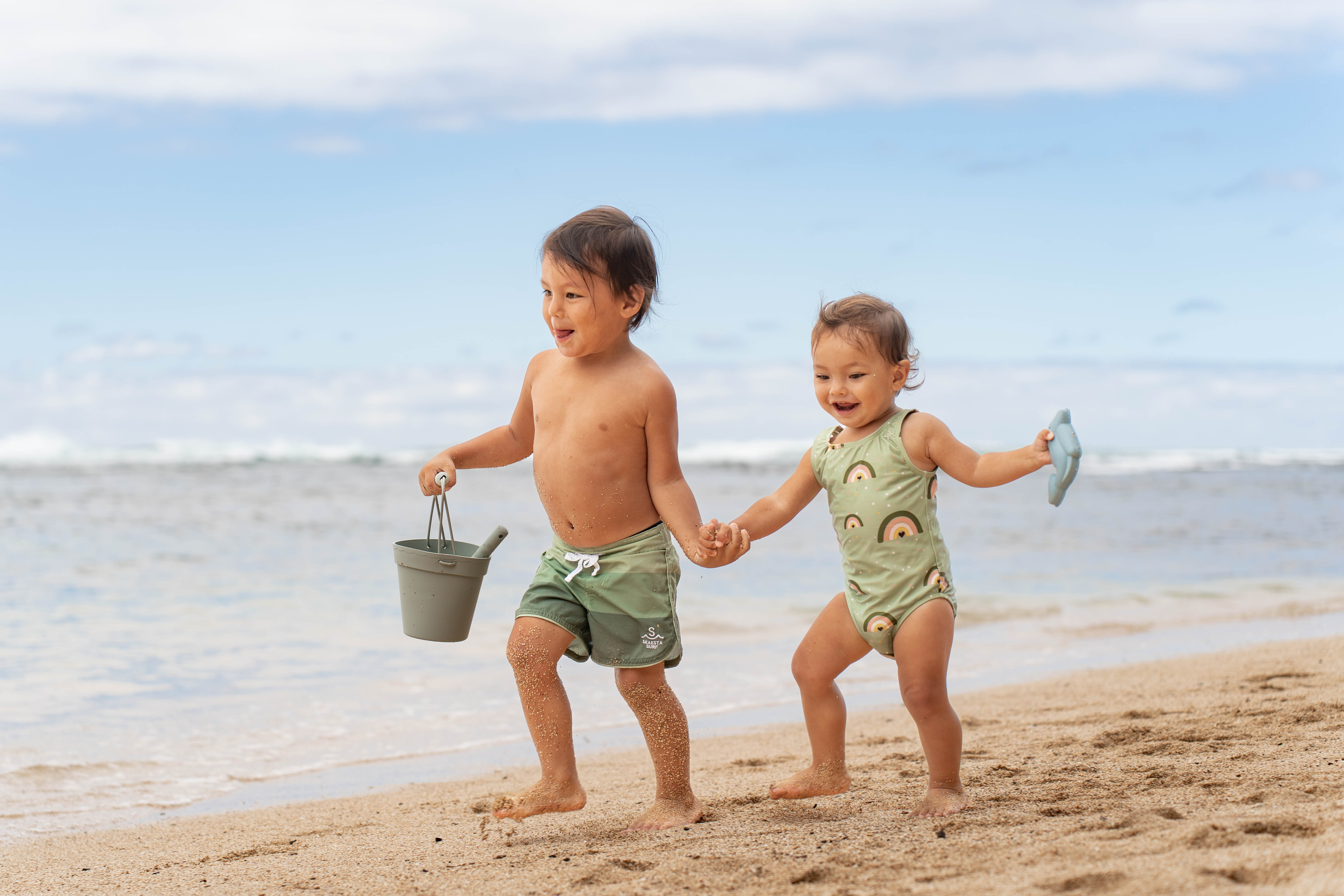 Deux enfants se tenant par la main et courant sur une plage