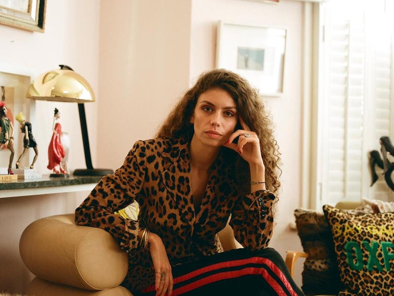 Brunette woman wearing a leopard print shirt poses for the camera while seated