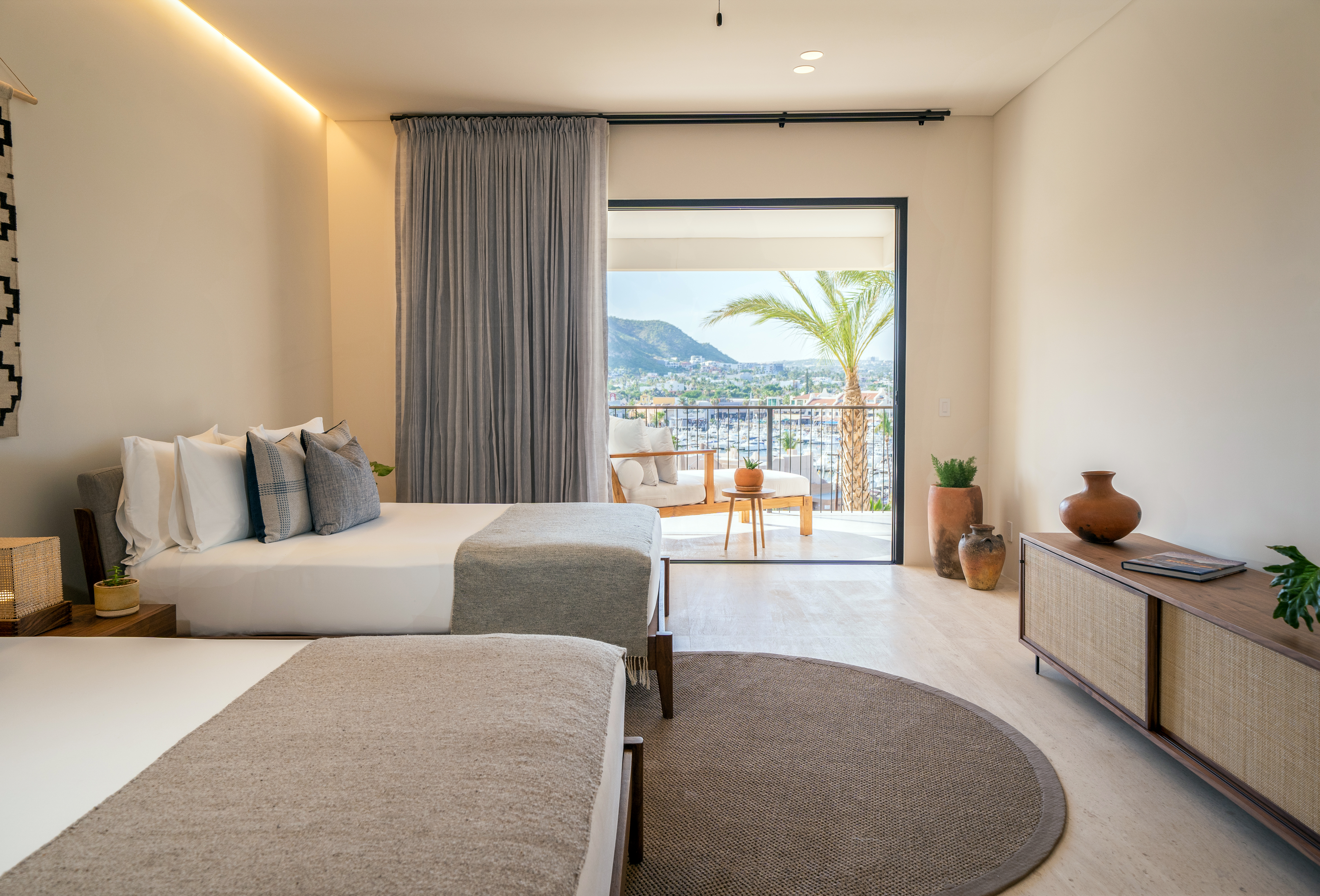 Two made beds with a patio looking out to the water