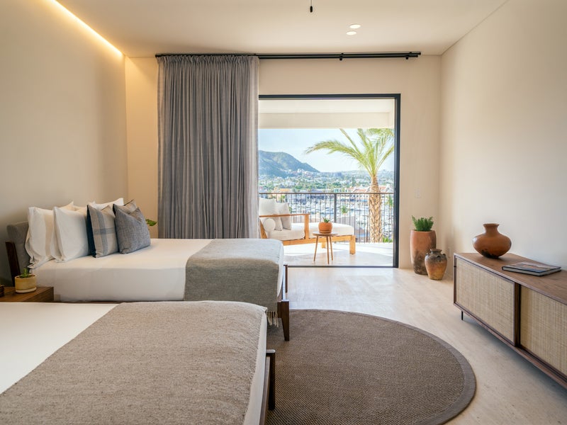 Two made beds with a patio looking out to the water