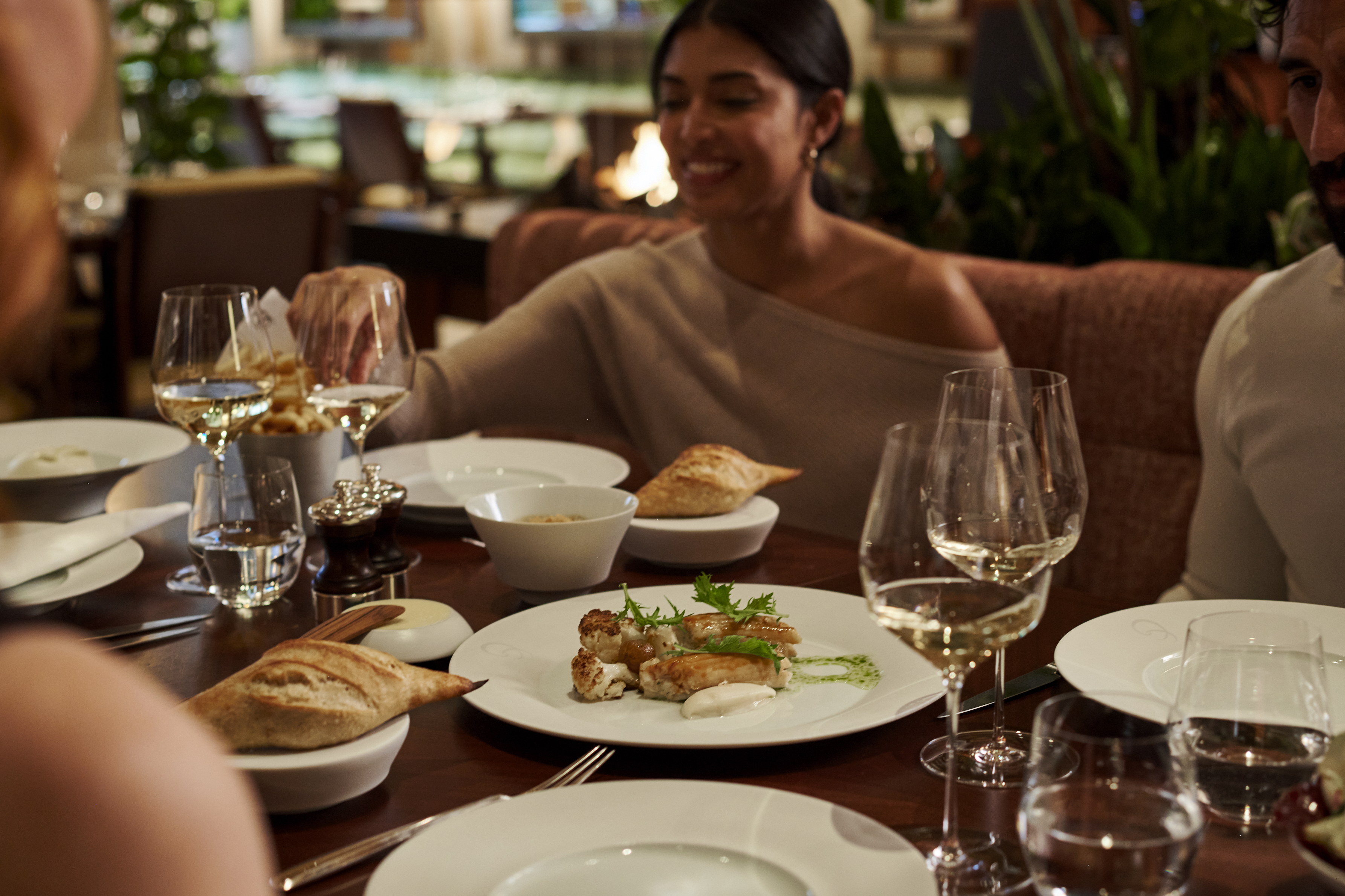 Woman and her friends having food and wine at wooden table