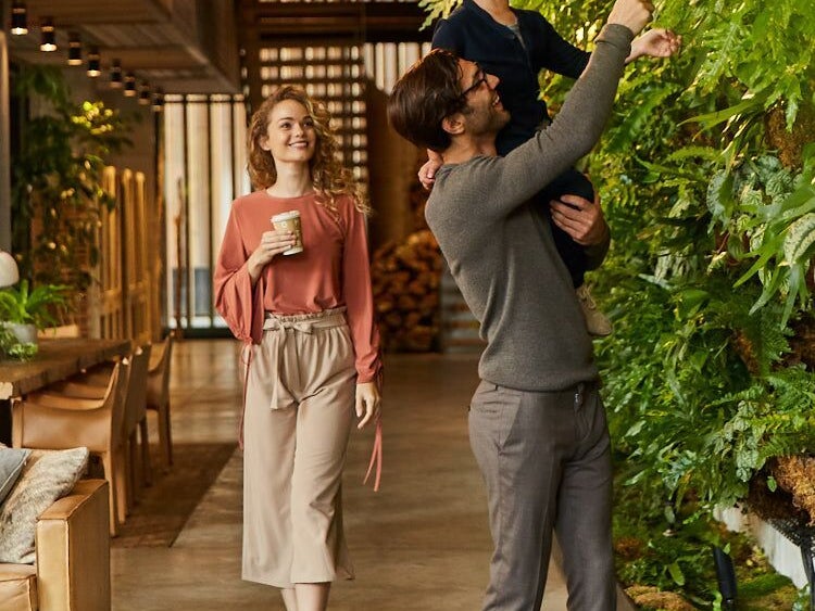 Father holding up his son to look at a living wall