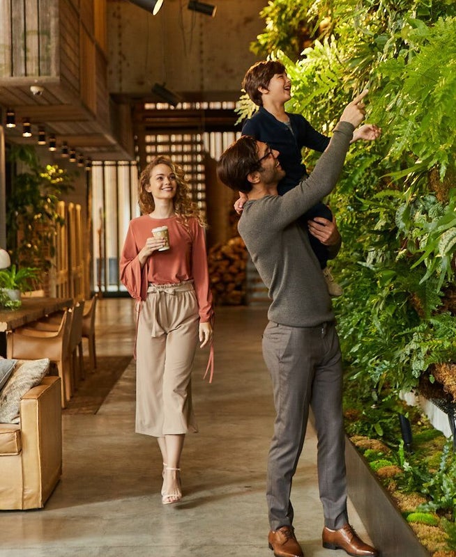 Father holding up his son to look at a living wall