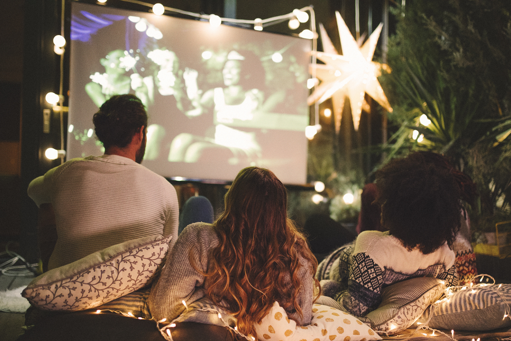 People watching a movie outdoors at night with a projector