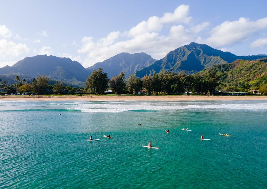 Guests enjoying the ocean using paddleboards with a view of the beach and mountain ranges