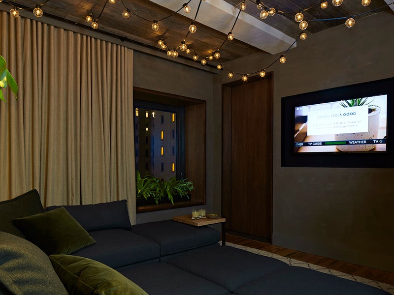Dimly lit room with a large couch and wall mounted tv