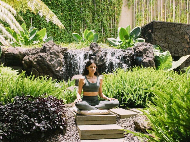 Woman Meditating surrounded by lush greenery