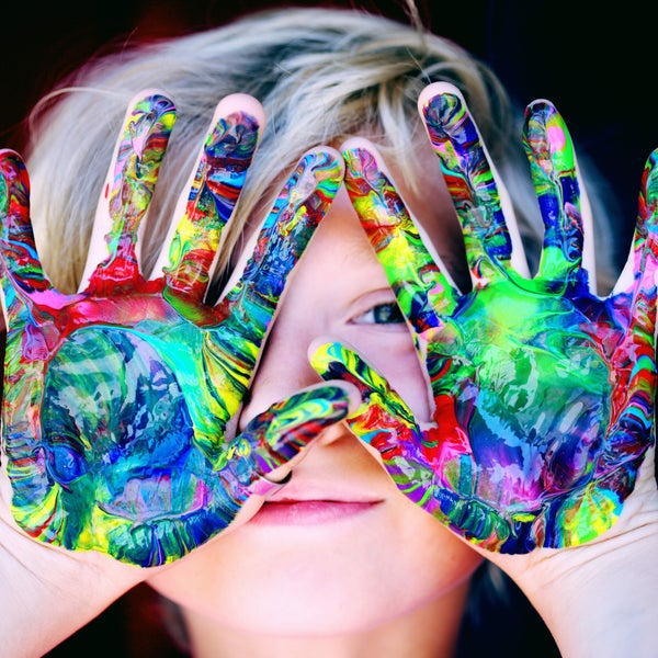 A child with painted hands covering their face