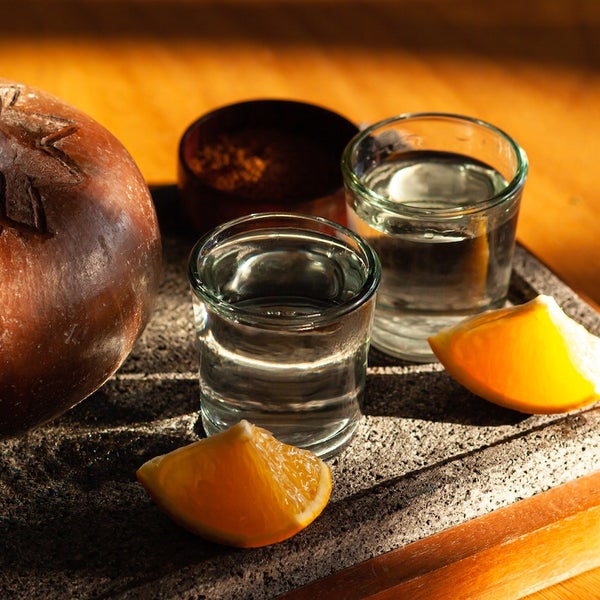 Two glasses of mezcal with an orange slice