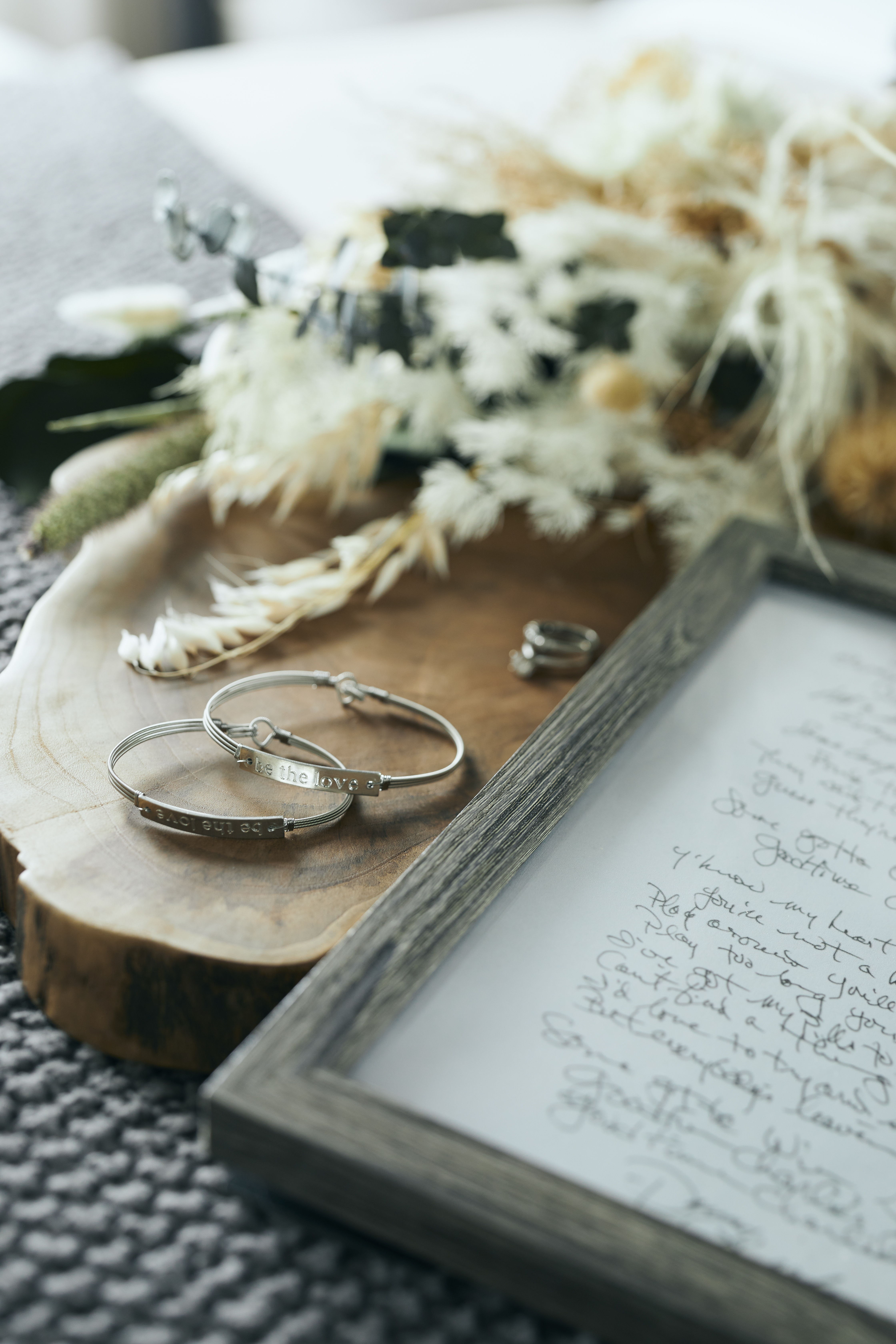 Two metal bracelets next to a wood frame hand written letter