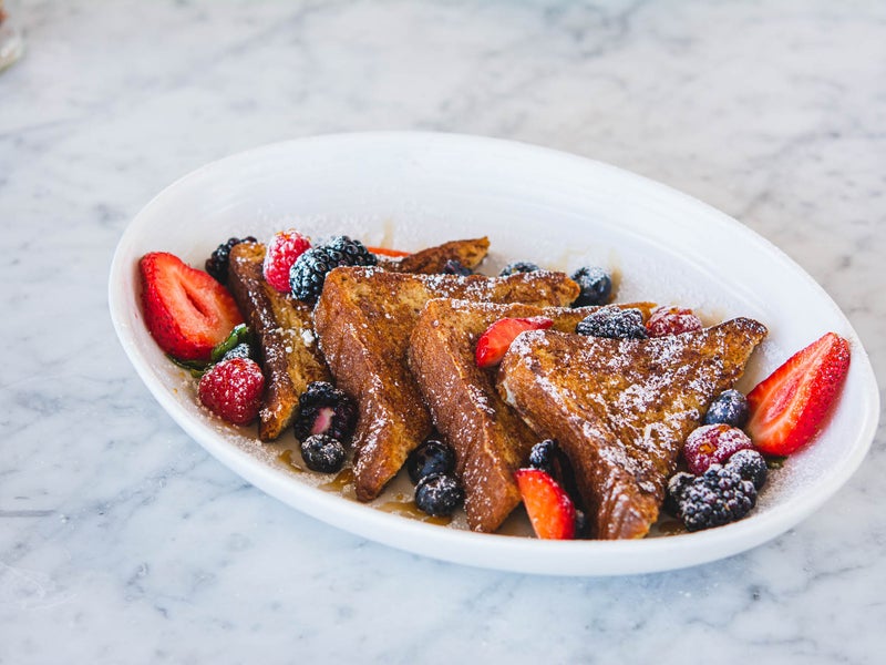 Bowl of french toast with syrup and berries