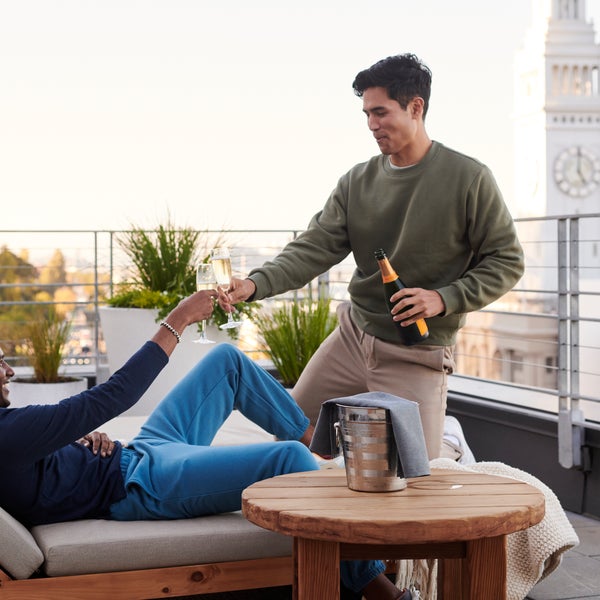 Two people sharing a glass of champagne on an outdoor patio