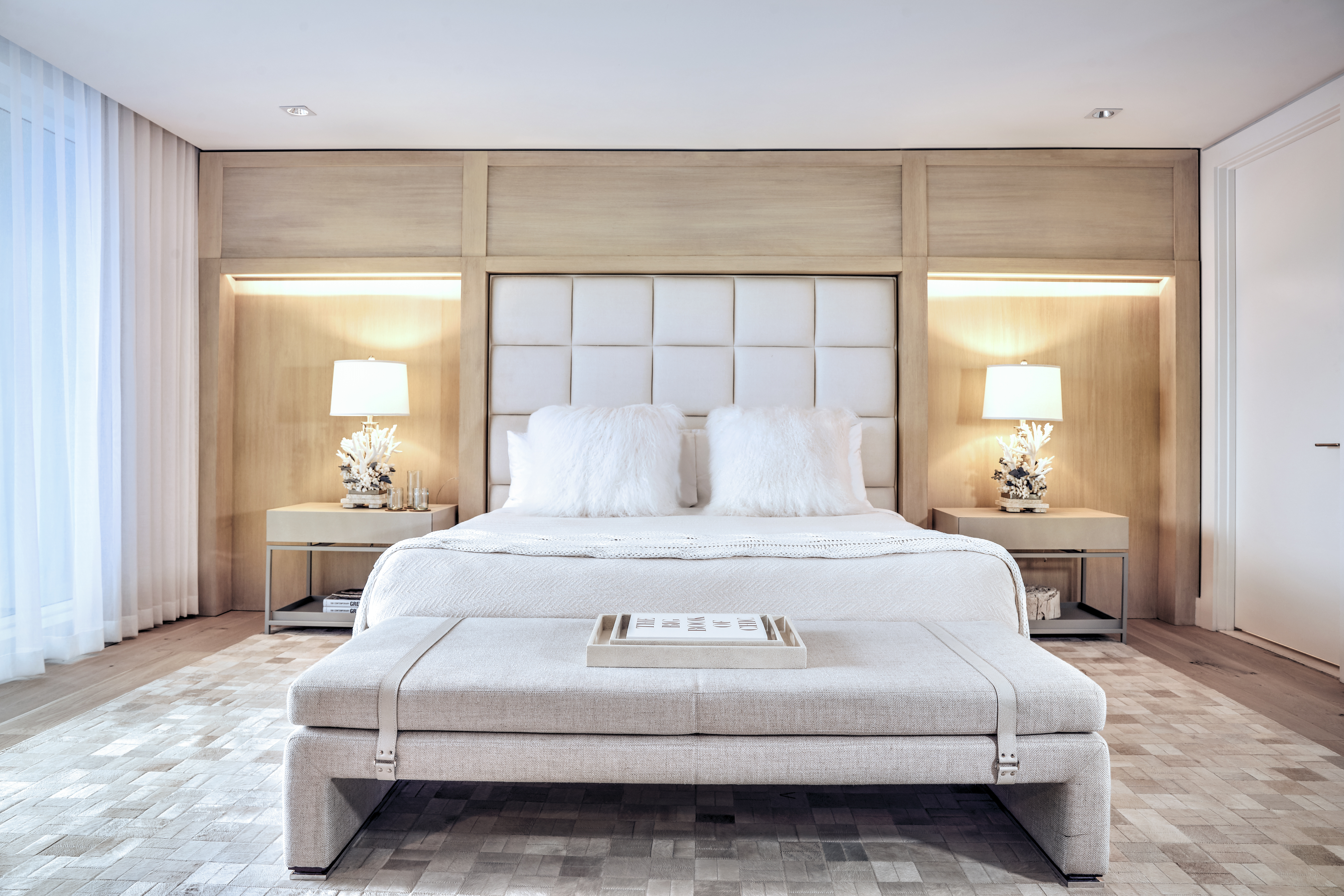 A made bed with a folding bench at the foot