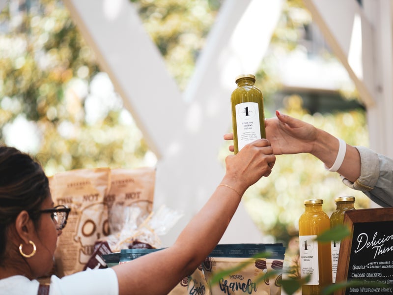A bottle of fresh pressed juice is handed to a female guest
