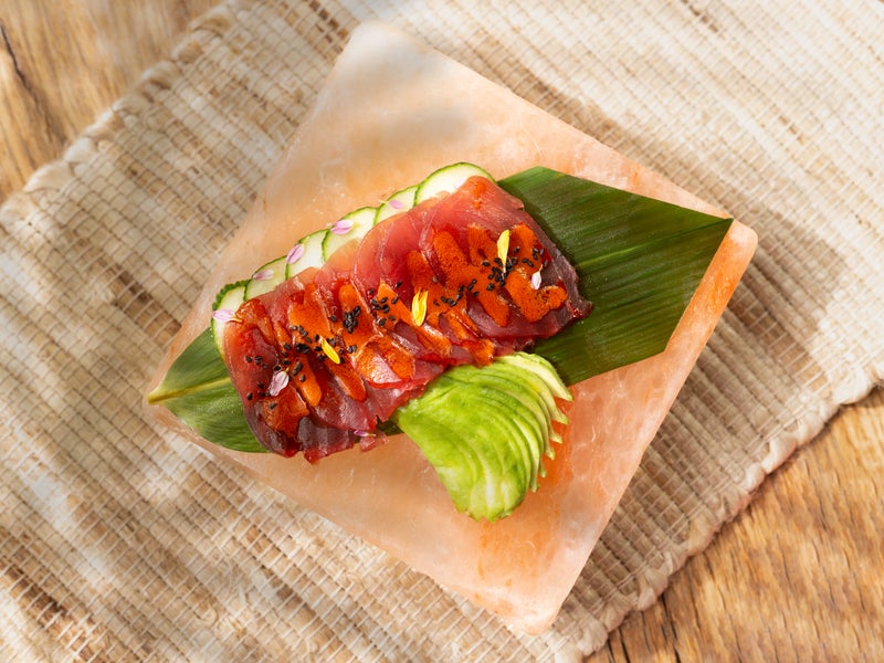raw tuna slices plated on a banana leaf