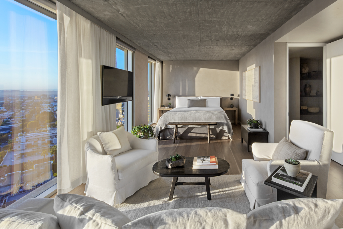 una camera con finestre a tutta altezza, un letto matrimoniale e mobili da salotto