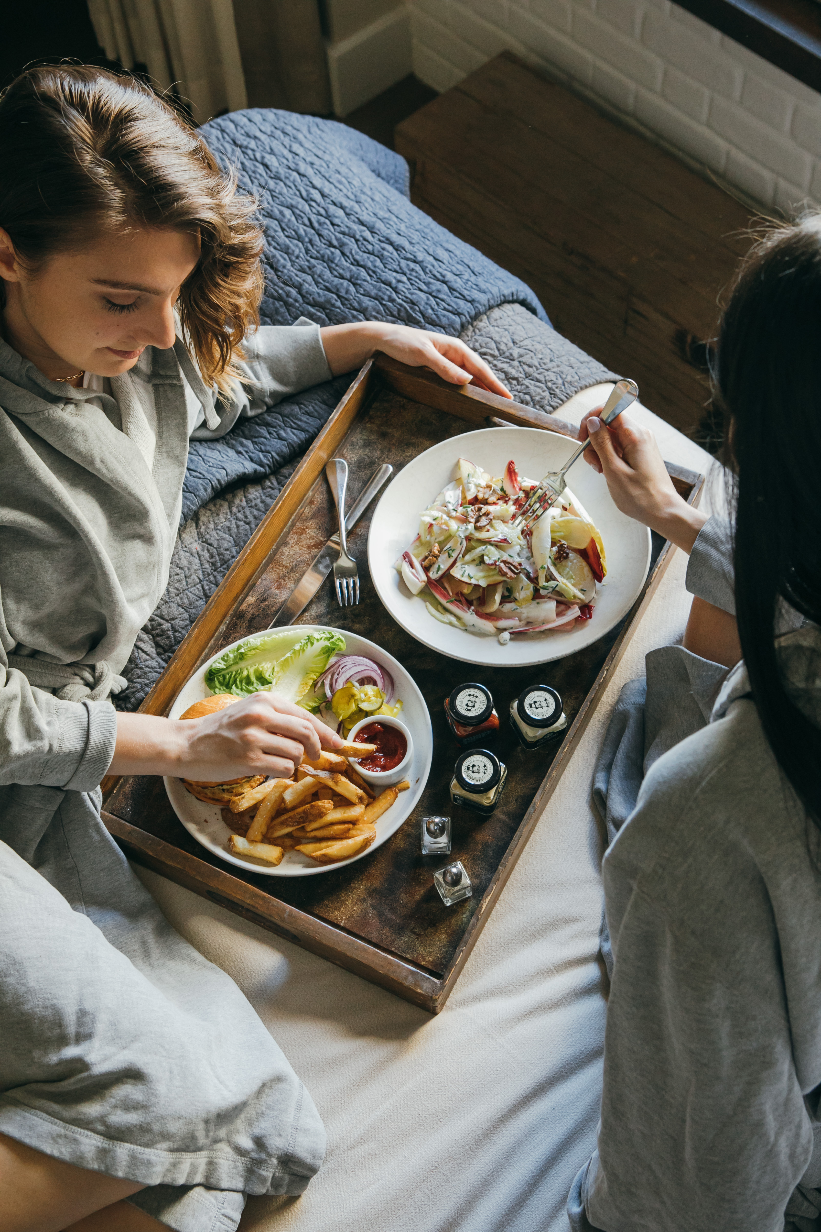 People eating food from a tray in bed