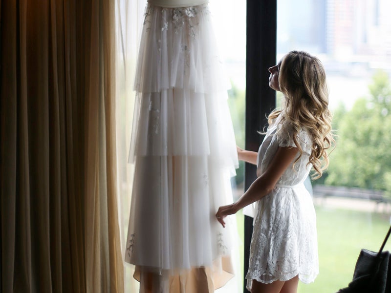 Bride admiring her hung up wedding dress 
