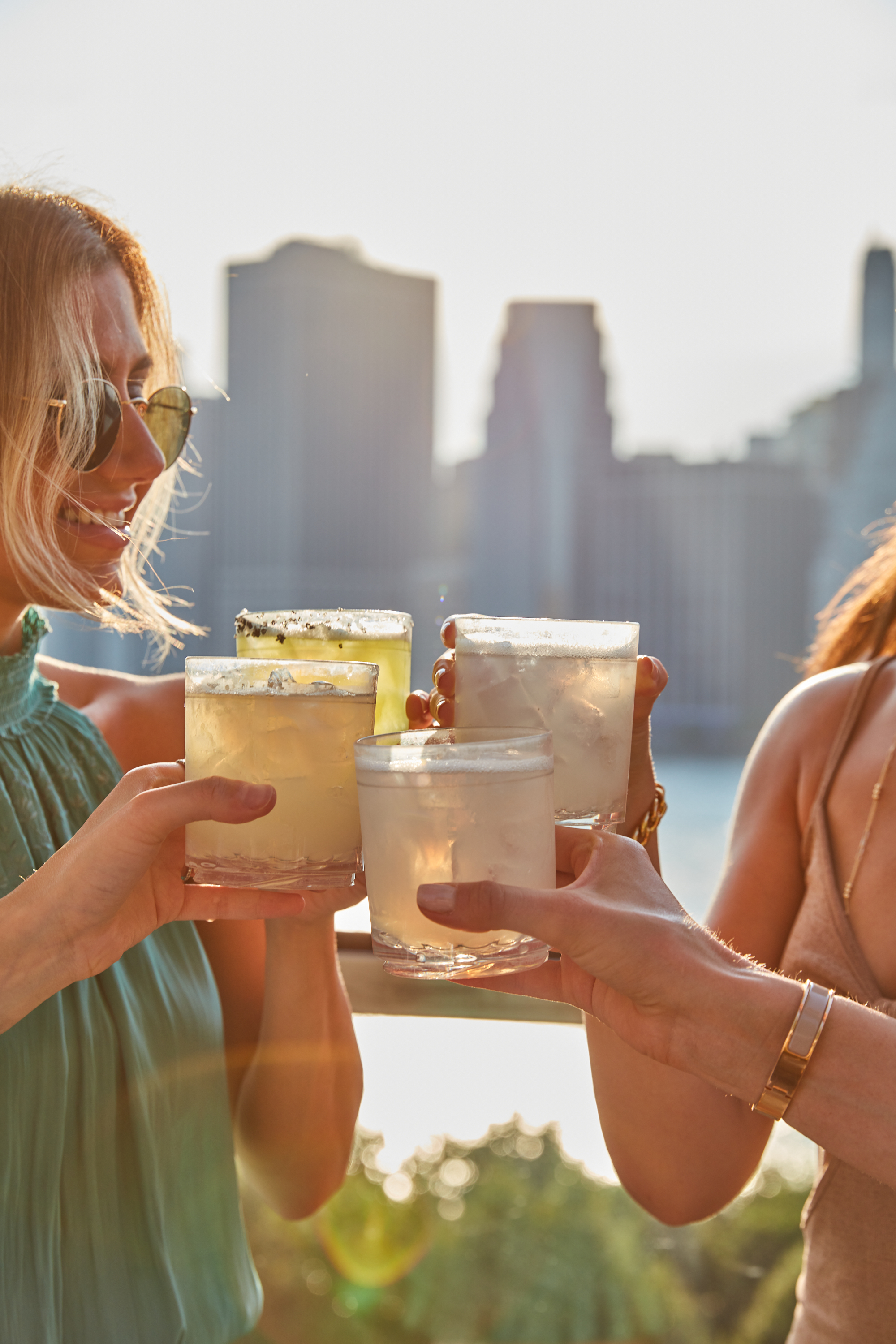 Four people cheers their drinks on the harriets rooftop patio