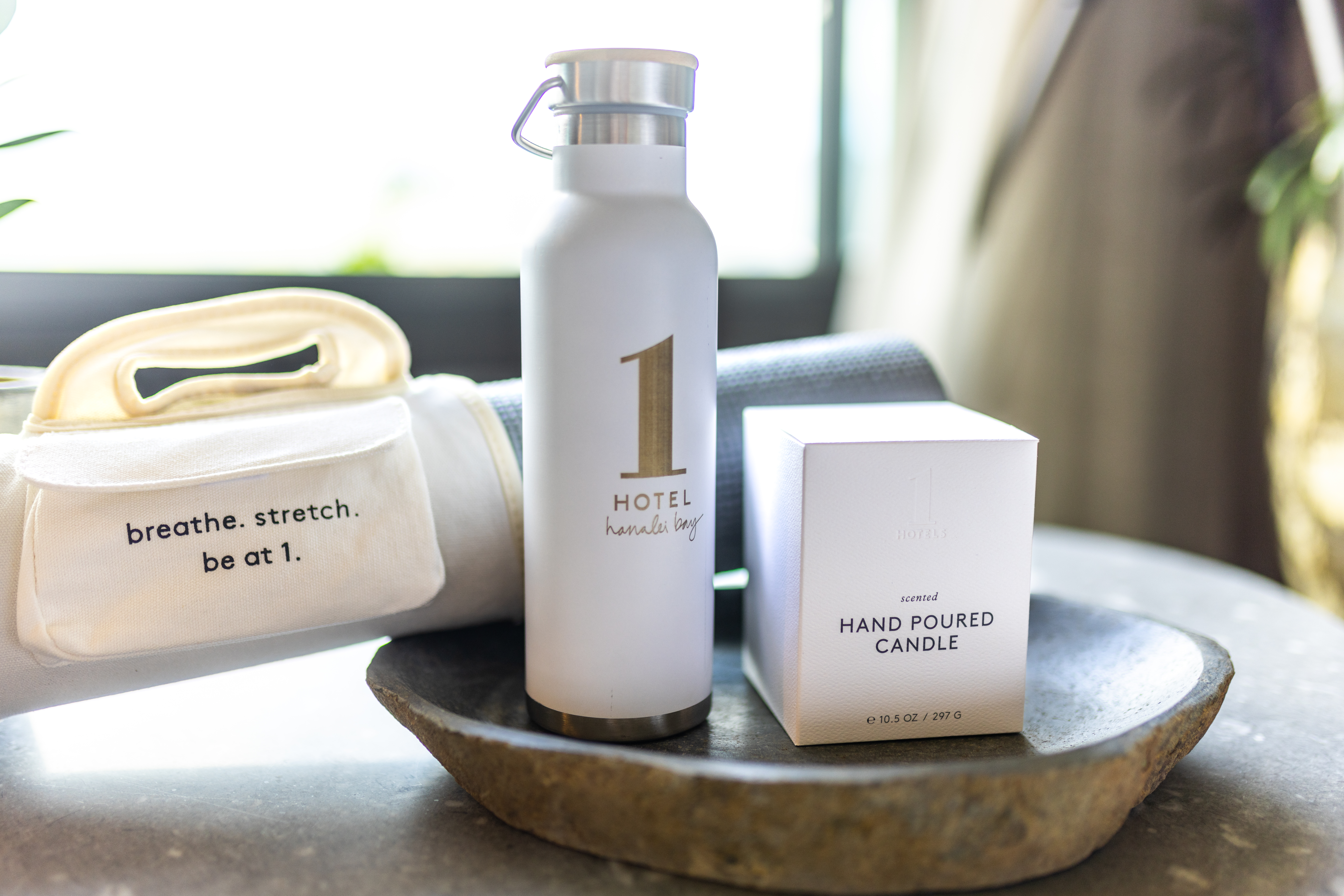 1 hotels scented candle, water bottle, and yoga mat