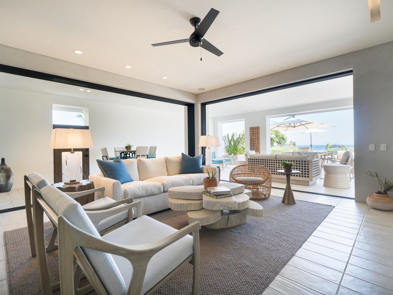 A large furnished room opens onto an outdoor patio with views of the ocean
