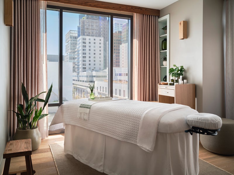 Massage table with a blanket over top with a window looking out at a city