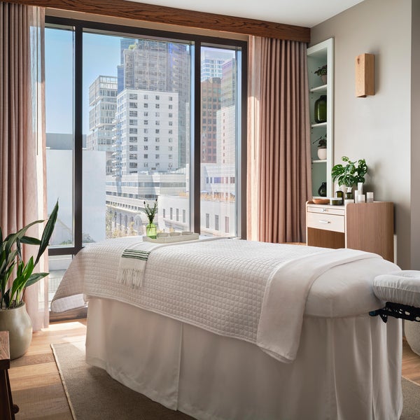 Massage table with a blanket over top with a window looking out at the city
