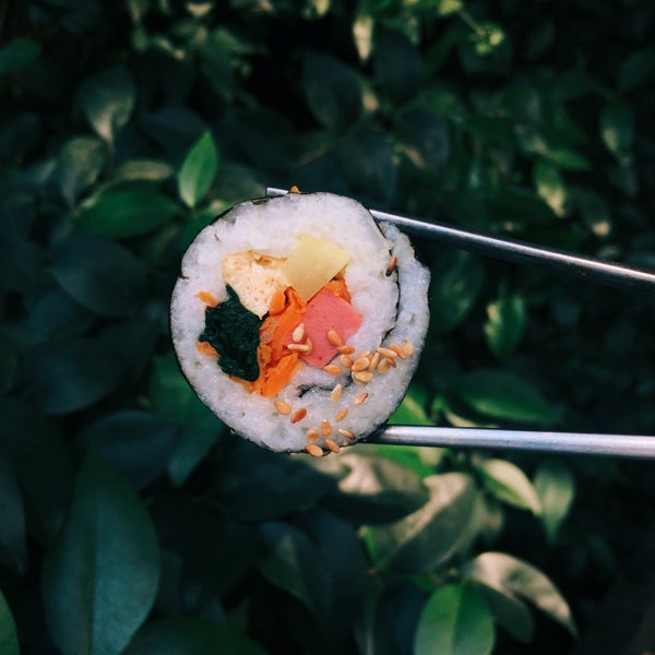 A sushi roll held in a pair of chopsticks