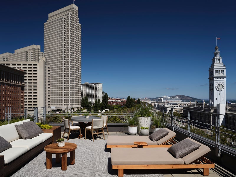 Patio sofa and reclined lounge chairs furnish the Ferry House Terrace suite with views of the San Francisco ferry building in the distance to the right