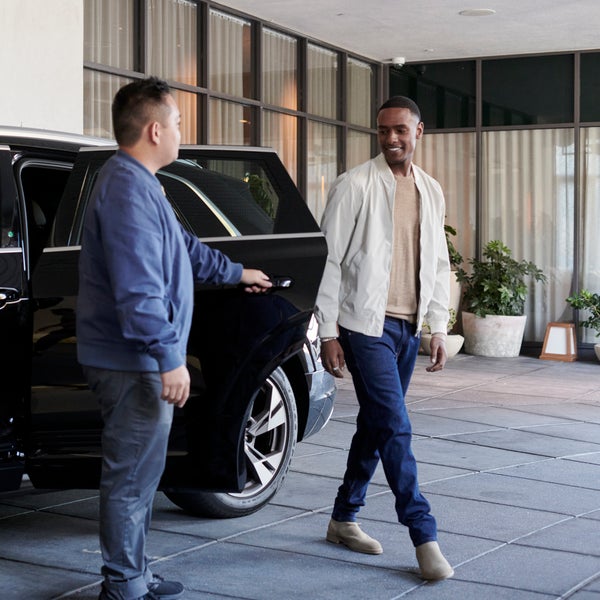 A valet welcomes guest who has just arrived in Audi e-tron house car