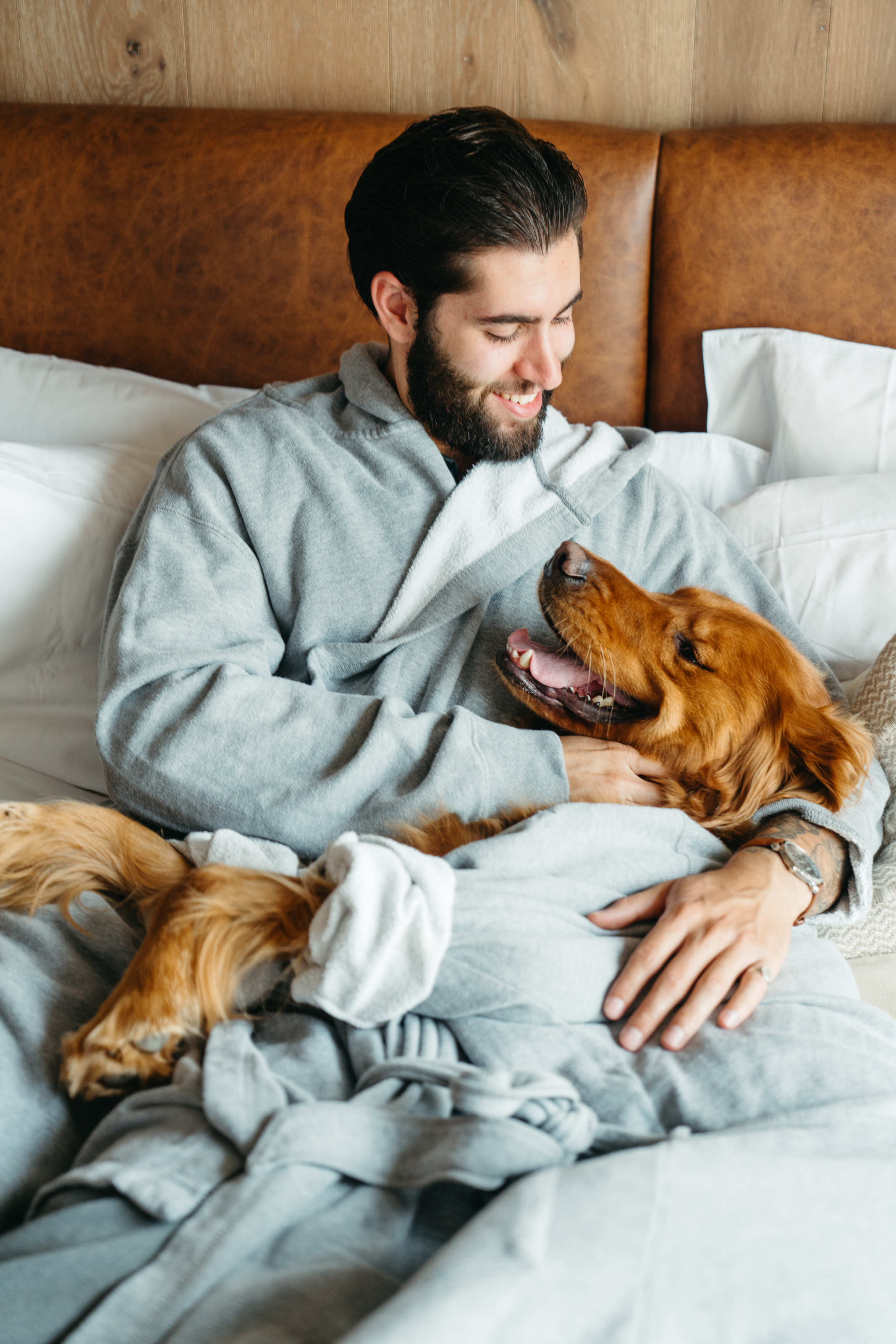 a man in a robe cuddling with his dog on a bed