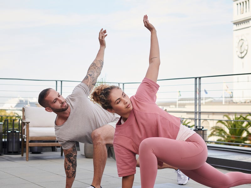 A couple practicing yoga on the rooftop