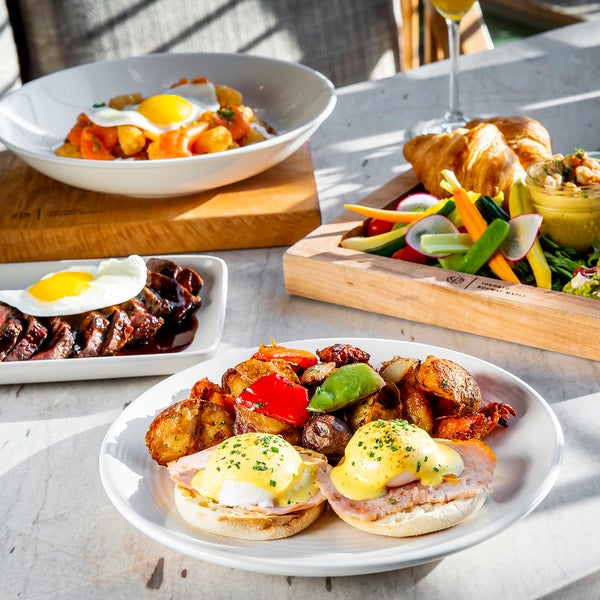 Various breakfast dishes pictured.  From left to right, steak and eggs, a breakfast skillet, eggs benedict, and a compliment of fresh veggies, croissants, and avocado toast