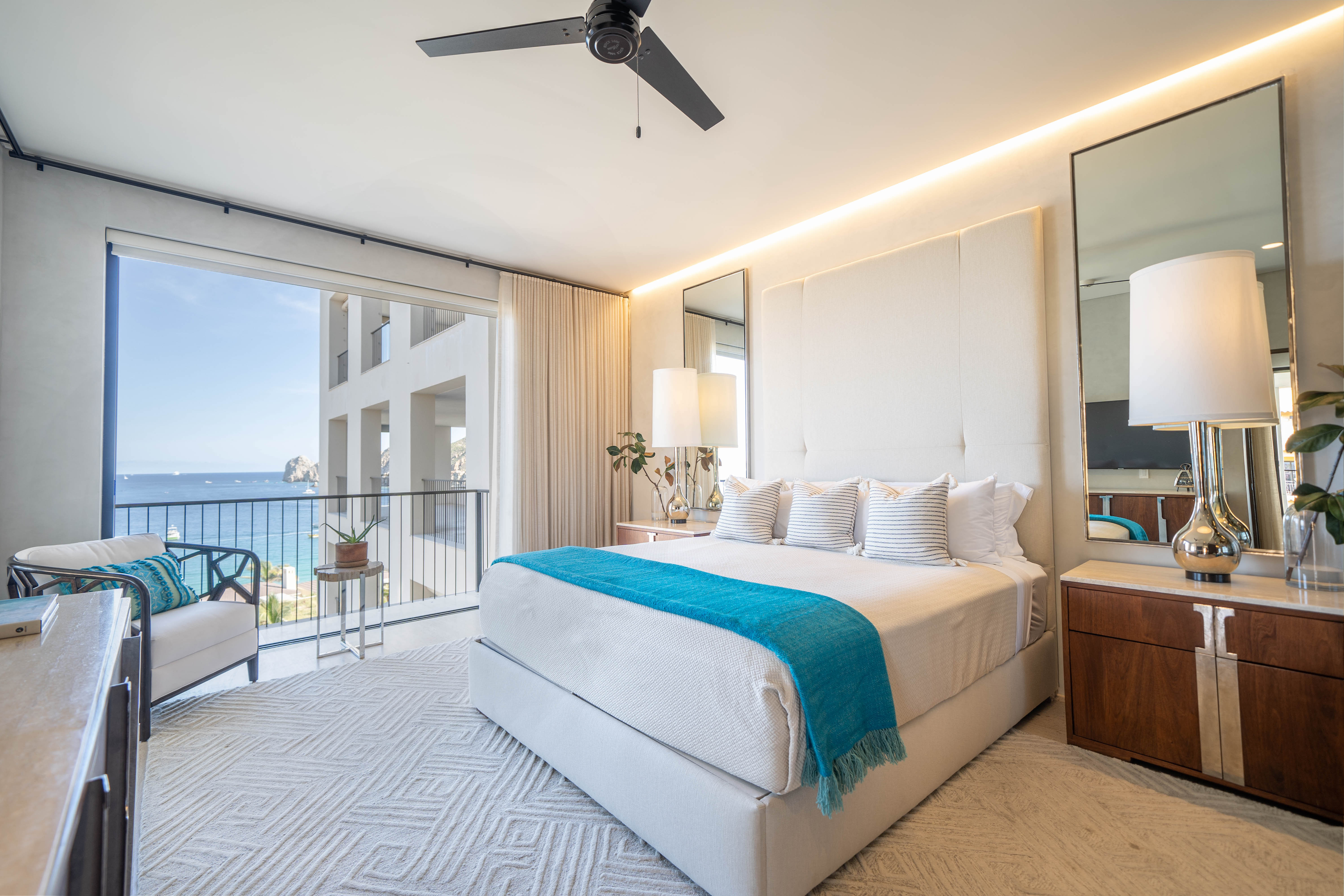 Bed with a blue blanket at the foot and a view outdoors