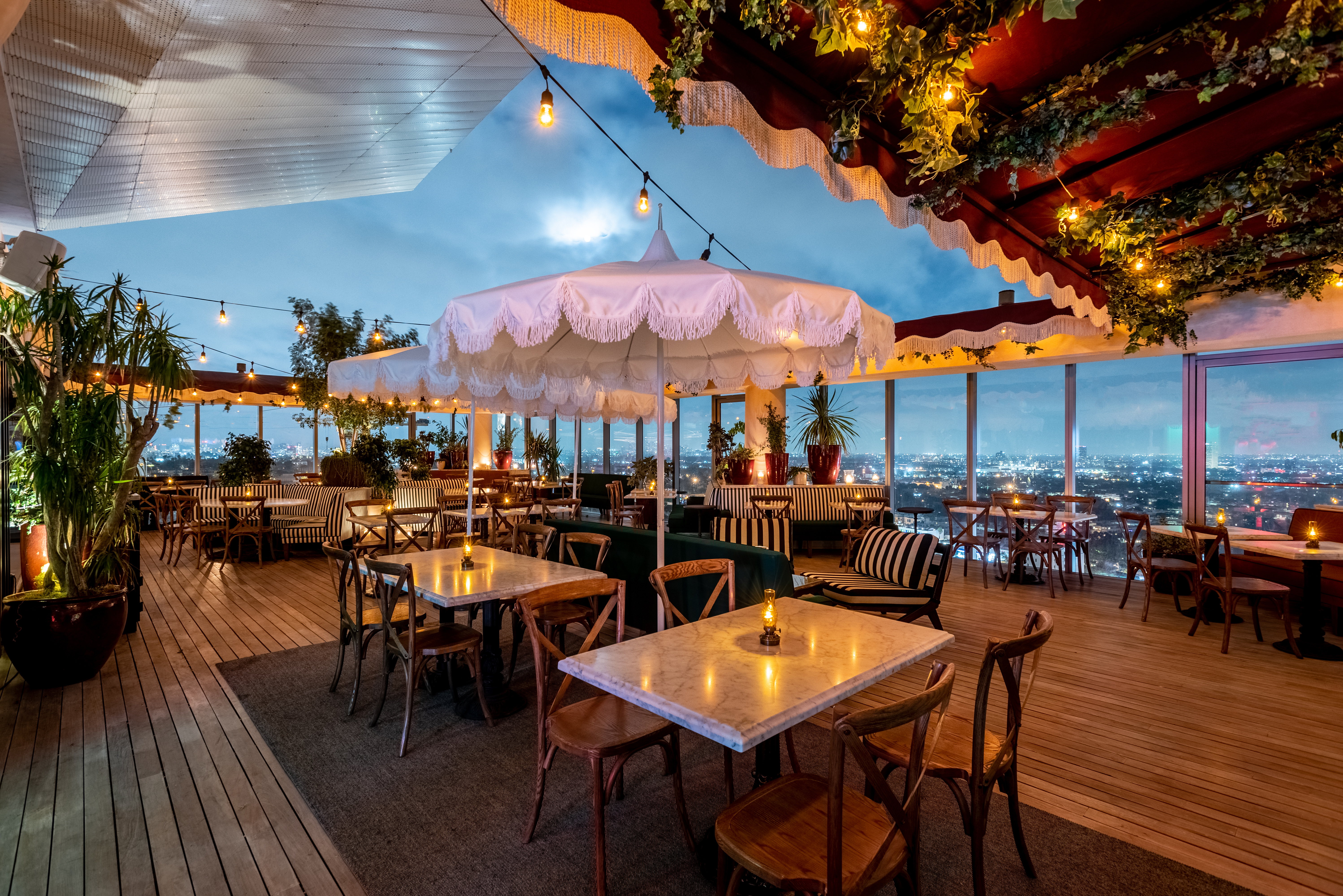 Een houten hekwerk omringt het dakrestaurant van Harriet bij zonsondergang. 