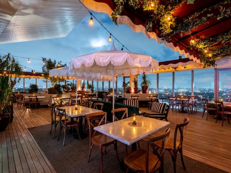 A wooden trellis wraps around the perimeter of the Harriet's rooftop restaurant at dusk. 