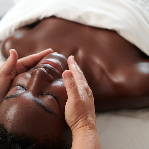 A woman lying face up on a massage bed receives a relaxing spa facial 