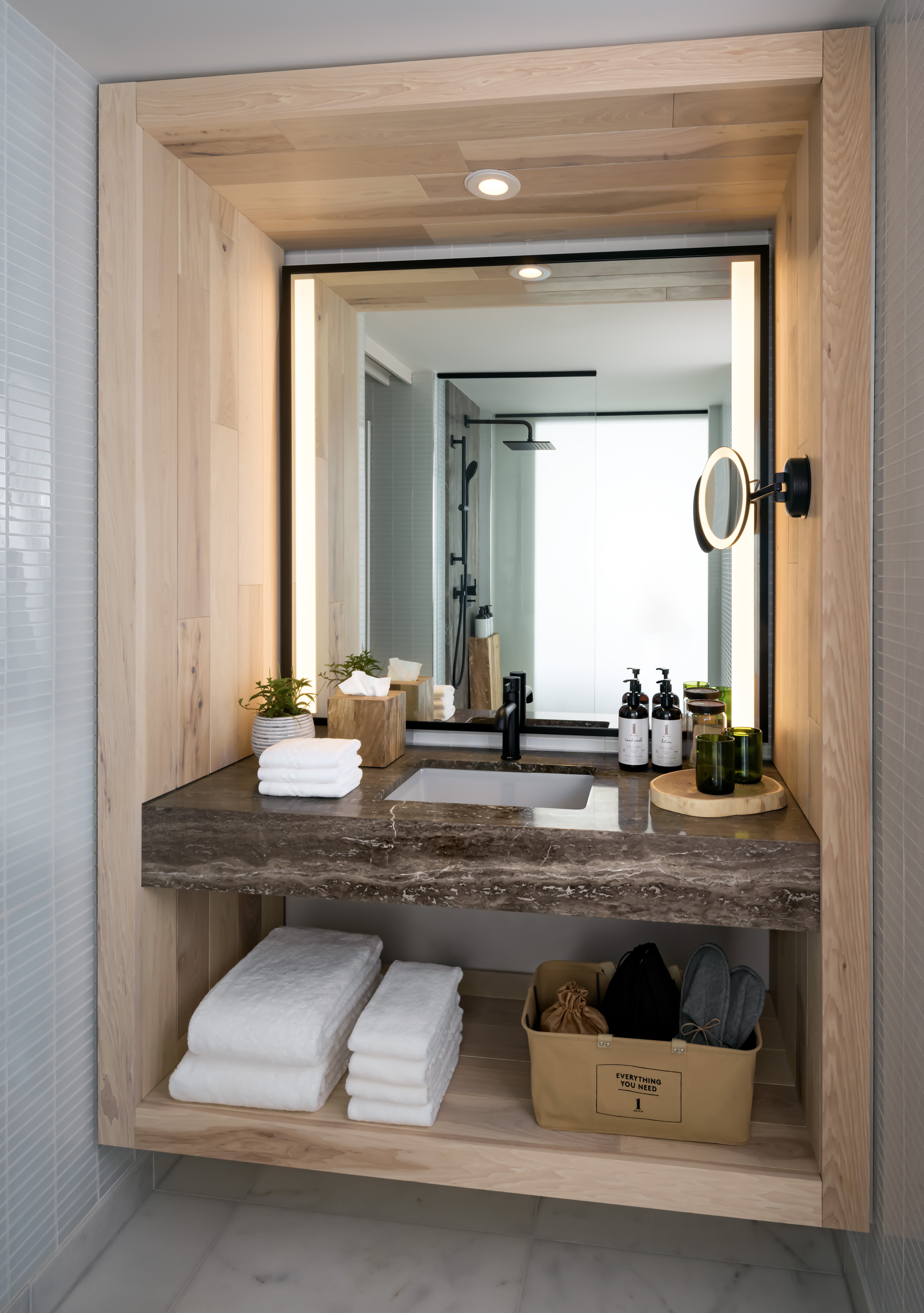 A bathroom sink with folded linen, granite countertop and backlit vanity mirror